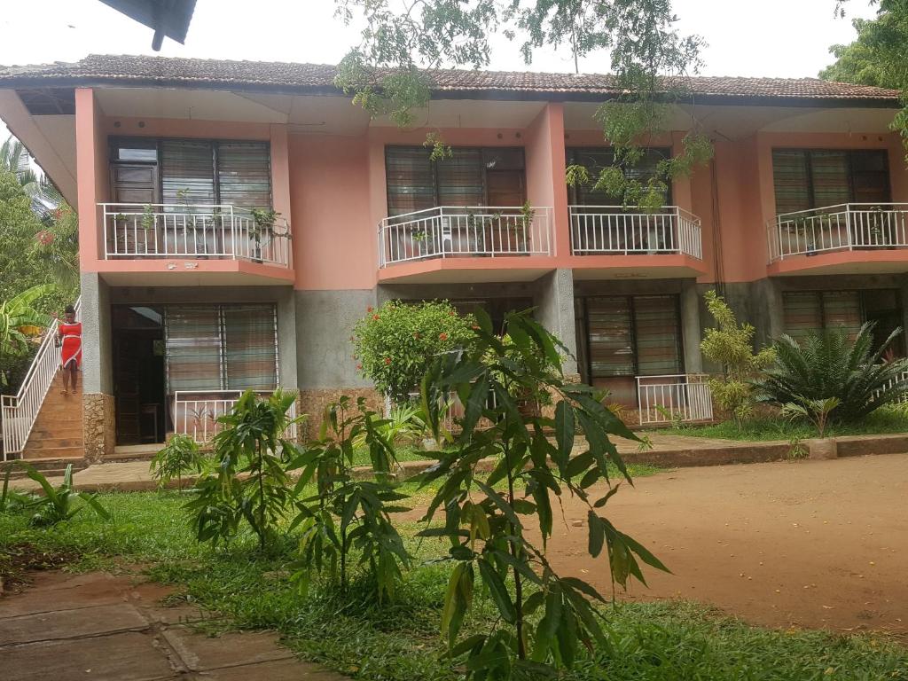 un edificio con balcones y árboles delante de él en PRIMESHADE GUESTHOUSE en Malindi