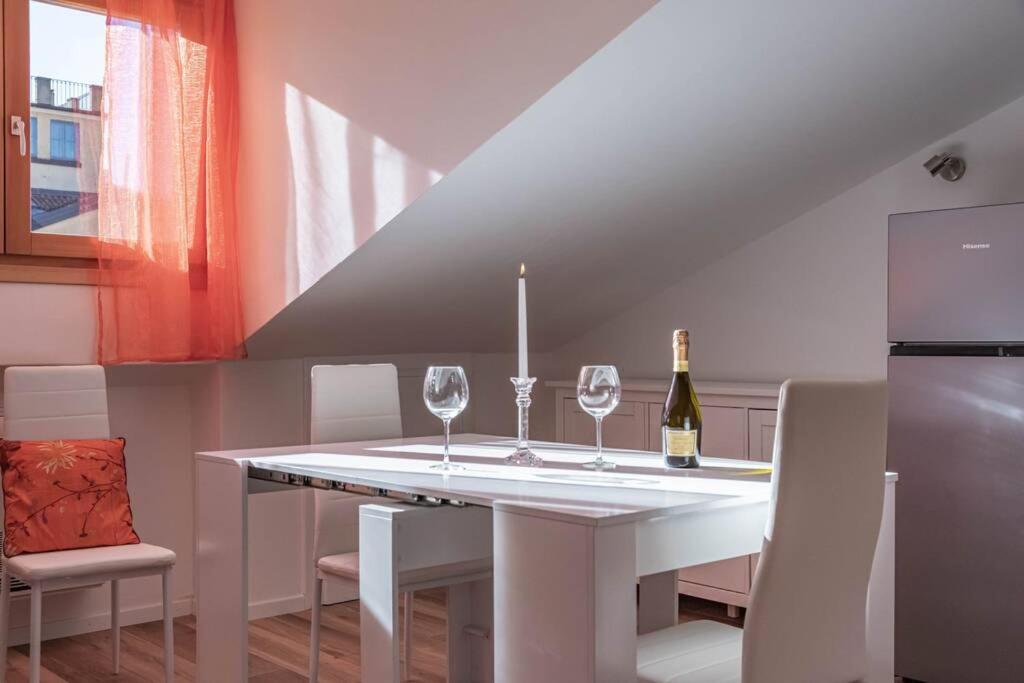 a white dining room table with two wine glasses on it at enJoy Home - Mansarda Piccolo Tesoro in Padova