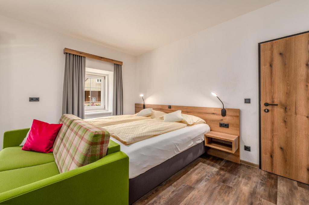 een slaapkamer met een bed en een groene bank bij Landgasthof Bierfriedl in Pruggern