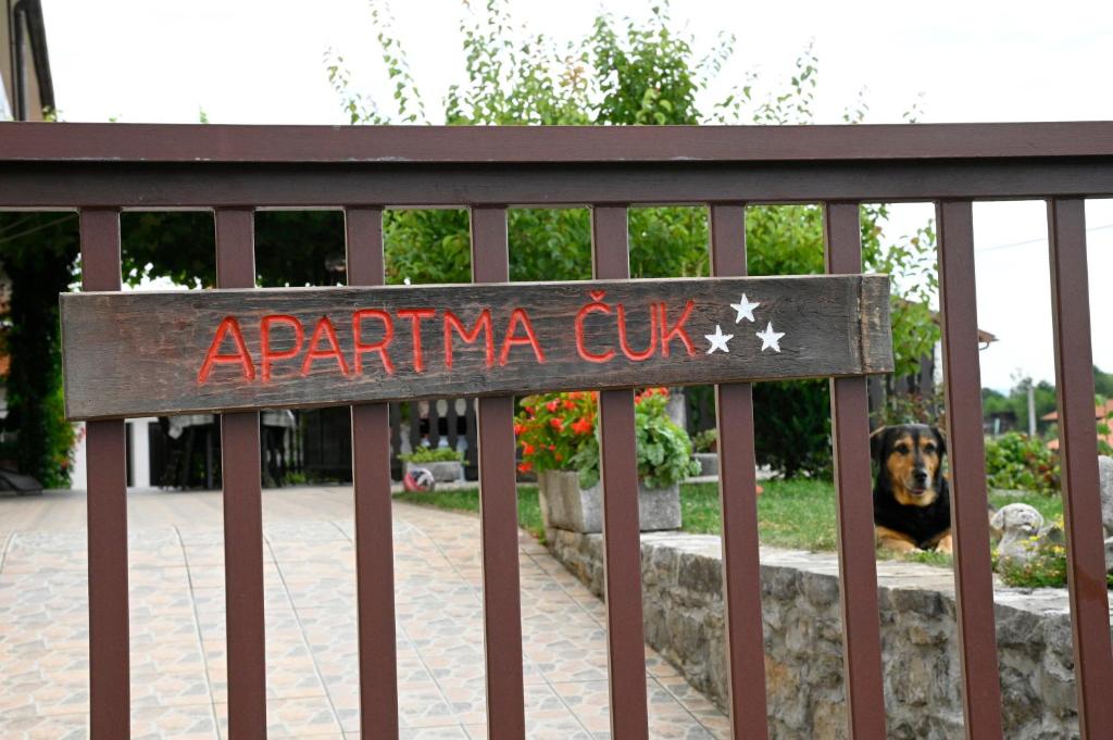 a sign on a fence with a dog behind it at Apartma Čuk in Dutovlje