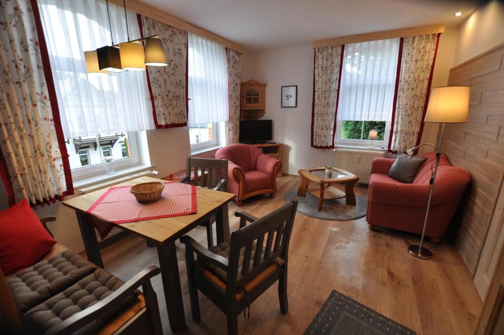 a living room with a table and chairs and windows at Wohlfühl-Ferienwohnungen König in Bad Elster