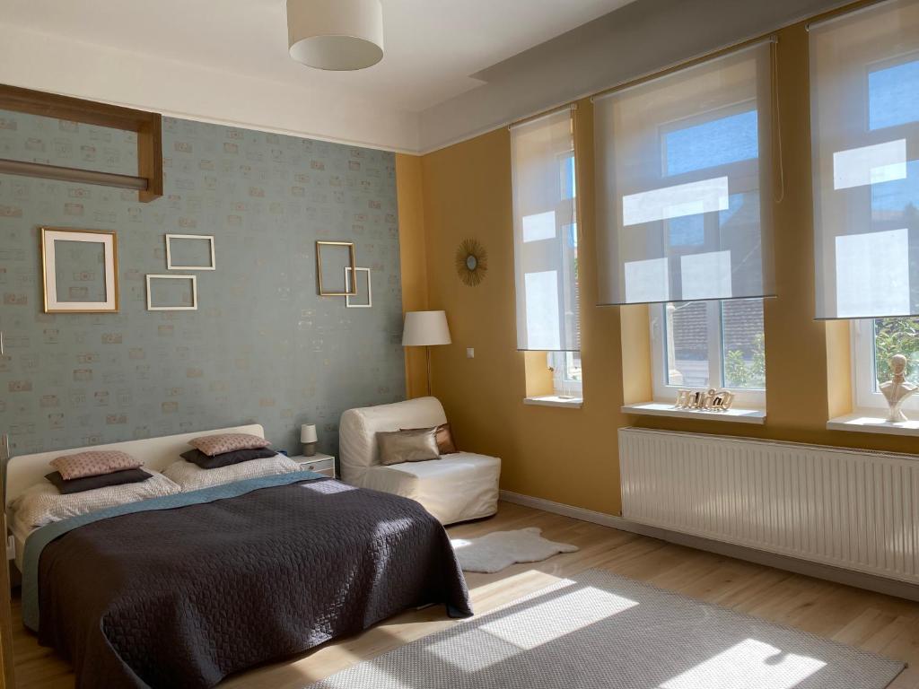 um quarto com uma cama, uma cadeira e janelas em STUDIO 18 em Sopron