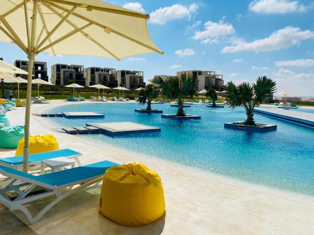 a swimming pool with lounge chairs and an umbrella at Fouka bay luxurious chalet in Marsa Matruh