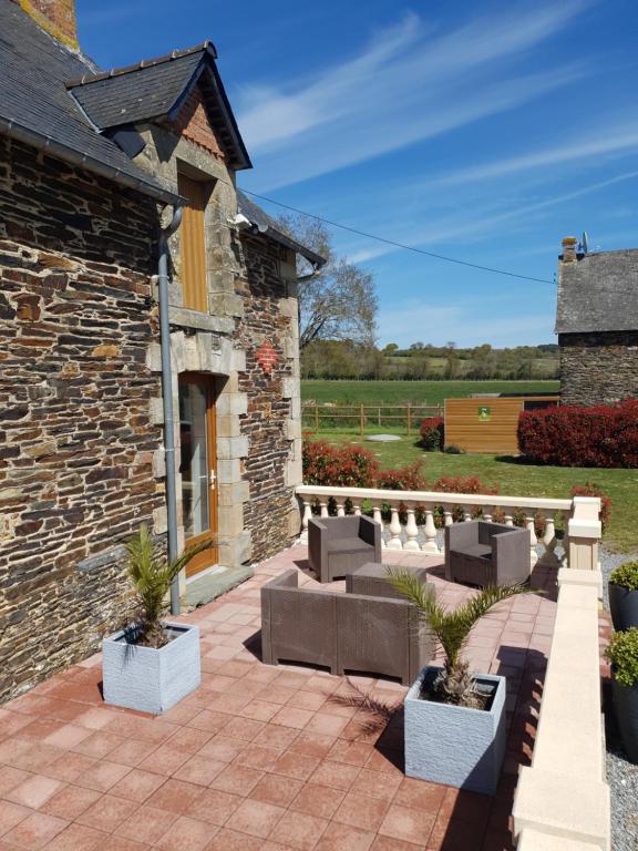 eine Terrasse mit Sofas und Pflanzen vor einem Gebäude in der Unterkunft La halte de la vilaine in Sainte-Anne-sur-Vilaine