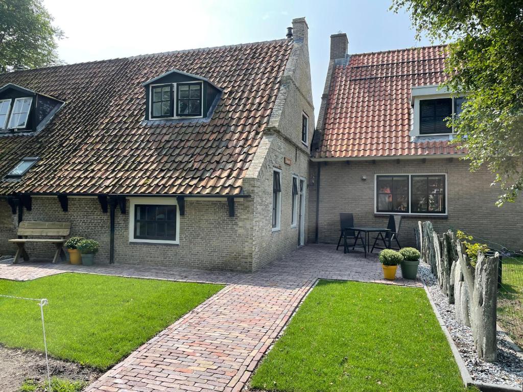 een stenen huis met een stenen loopbrug in de tuin bij Kakebiën in Hollum