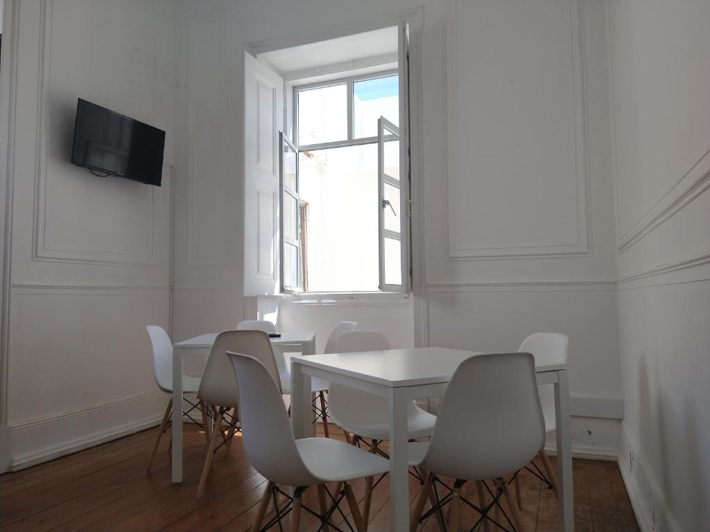 a white dining room with a white table and chairs at Baixa Terrace Hostel in Faro