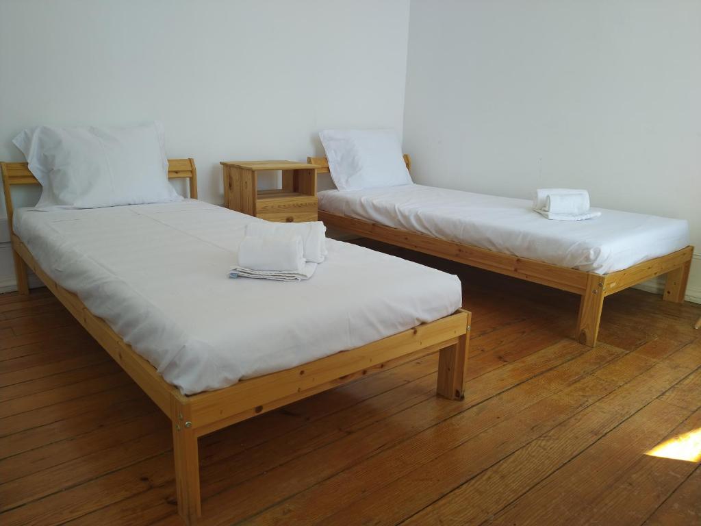 two twin beds in a room with wooden floors at Baixa Terrace Hostel in Faro