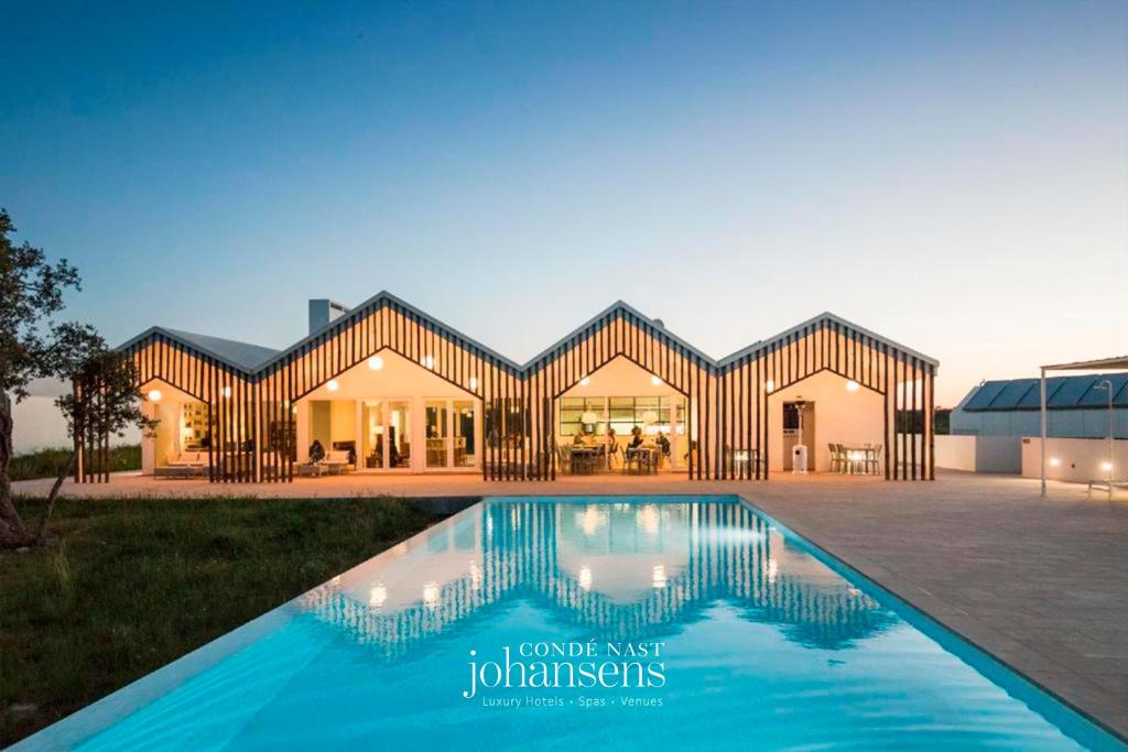 a house with a swimming pool in front of it at Sobreiras Alentejo Country Hotel - by Unlock Hotels in Santa Margarida da Serra