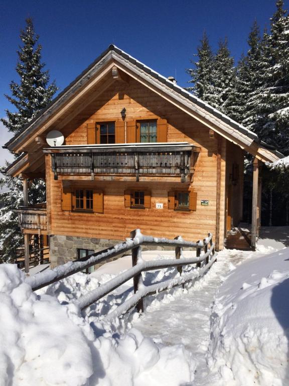 une cabane en rondins avec une clôture dans la neige dans l'établissement Horská chata KorAlpe, à Hartelsberg