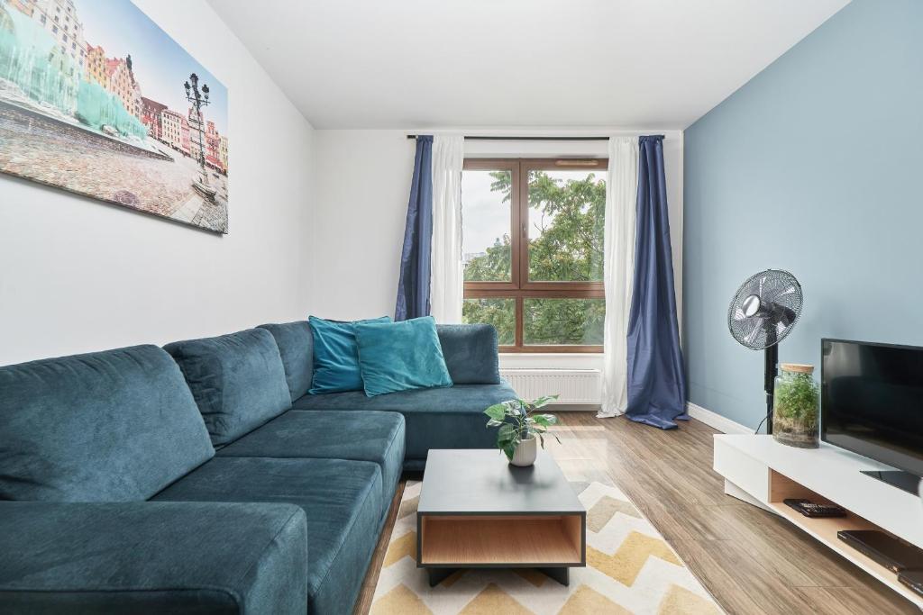 een woonkamer met een blauwe bank en een tv bij Apartments Odra Tower Wrocław by Renters in Wrocław