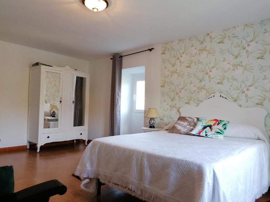 Un dormitorio con una cama blanca y una pared con flores en Casa Cándida 4 habitaciones, en Viascón