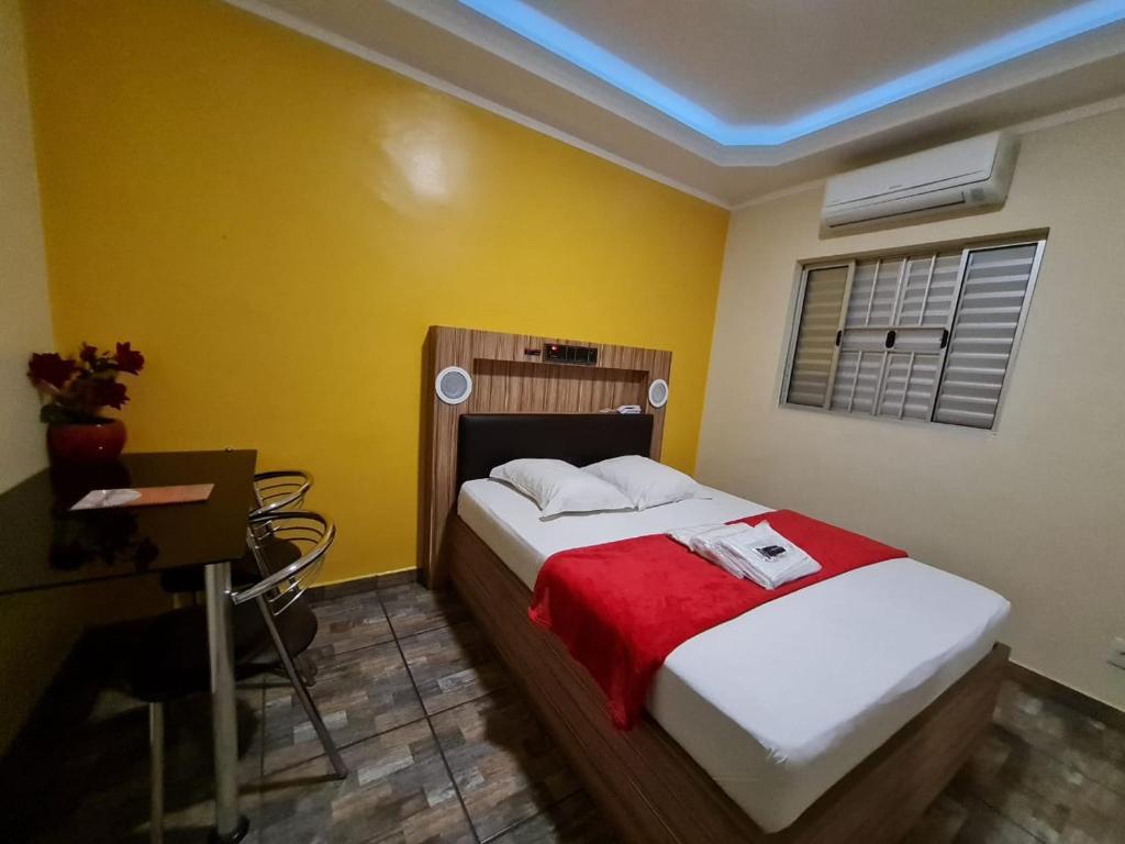 a bedroom with a bed and a desk and a window at PENSEENTRE MOTEL in Rio Claro
