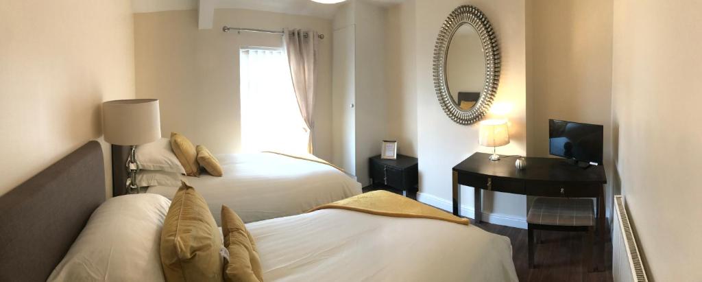 een slaapkamer met 2 bedden, een spiegel en een bureau bij Mountain View Aberavon Beach, Afan Valley & Margam Park, South Wales in Port Talbot