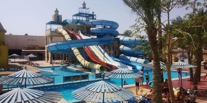 a water slide in a swimming pool with umbrellas at One Bedroom Suite with Aqua View at Mirage Bay Resort in Hurghada