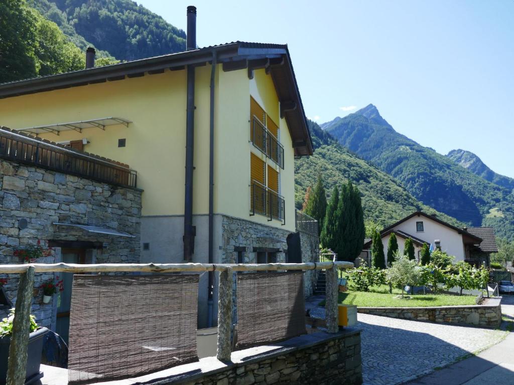 a house with a fence and mountains in the background at Apartment Lety by Interhome in Malvaglia
