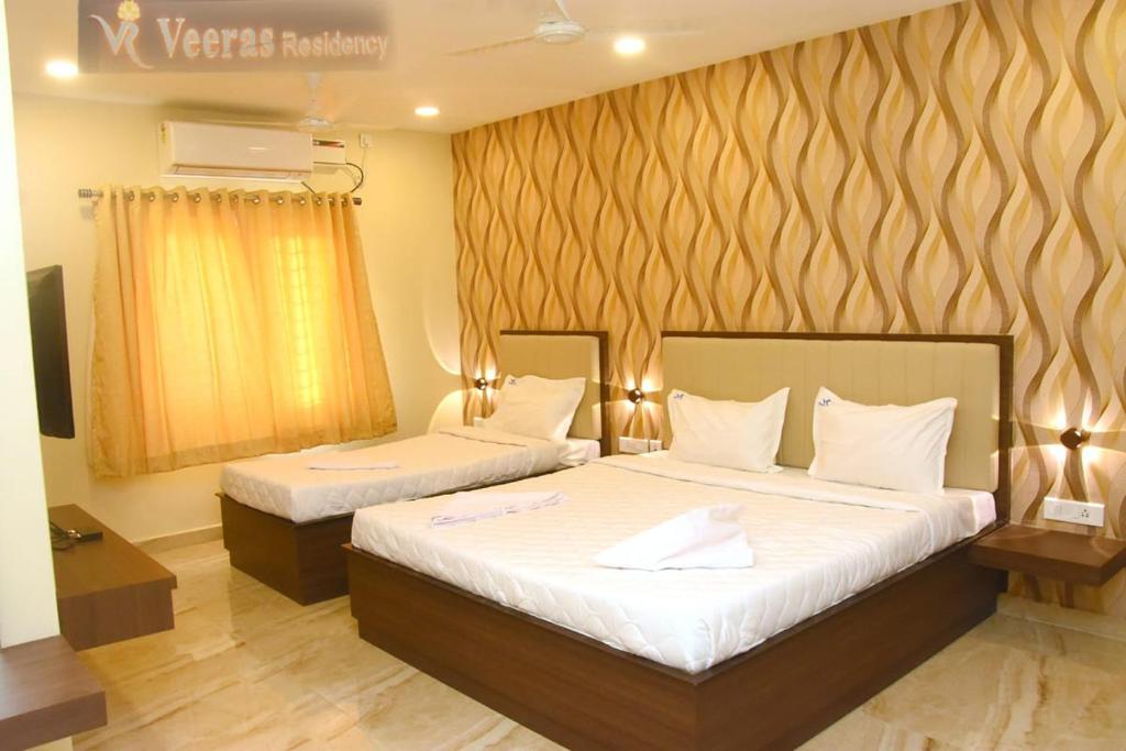 a bedroom with two beds with white sheets at Veeras Residency in Pondicherry