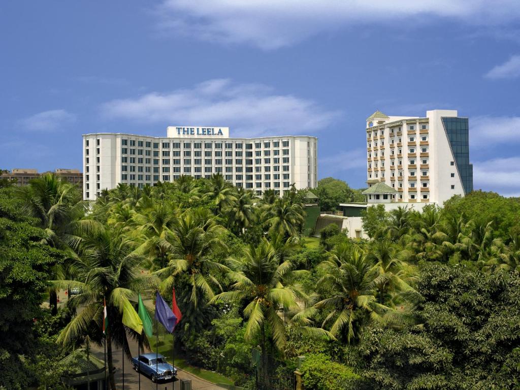 a hotel with palm trees in front of a building at The Leela Mumbai in Mumbai