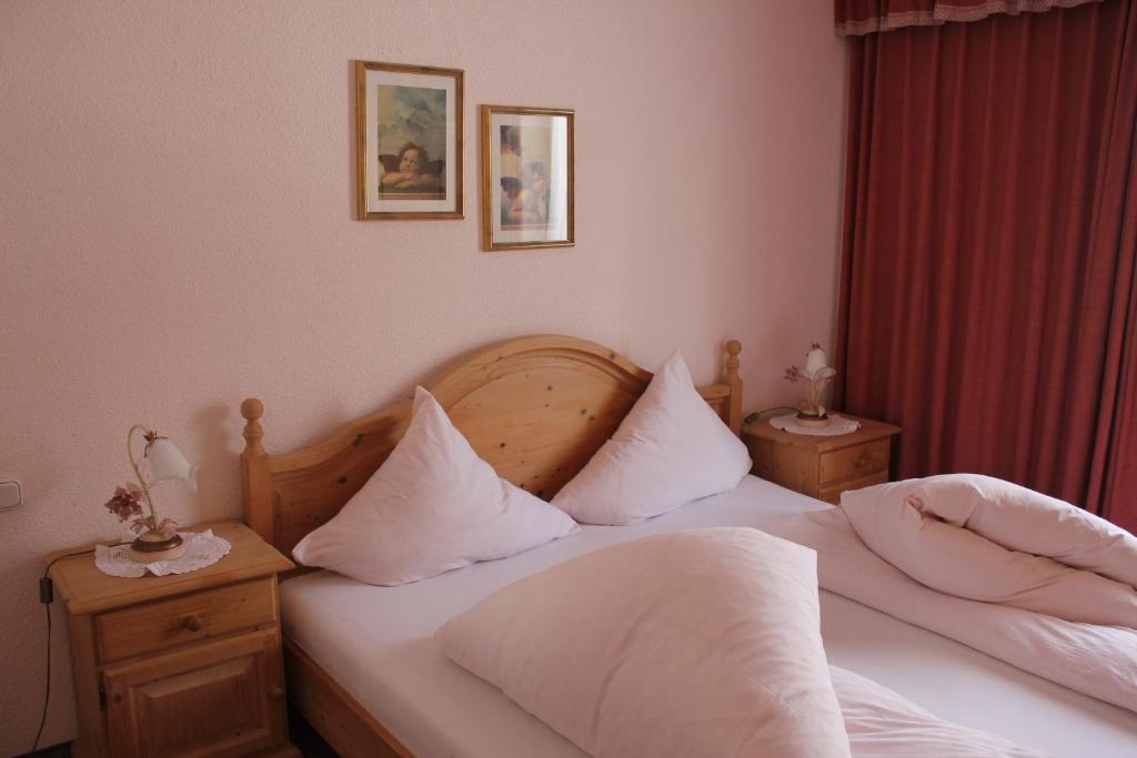 Schlafzimmer mit einem Bett mit weißer Bettwäsche und Kissen in der Unterkunft Waldvilla am See in Pertisau
