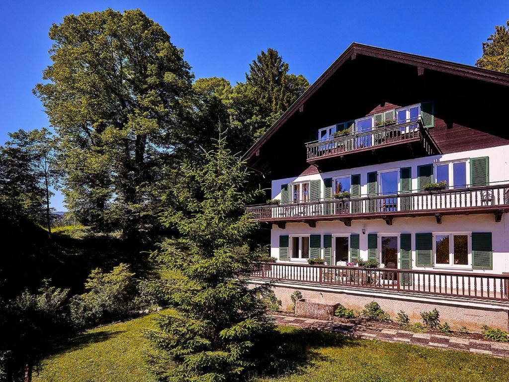 ein großes weißes Haus mit einem Balkon und einem Baum in der Unterkunft Villa Sawallisch in Grassau