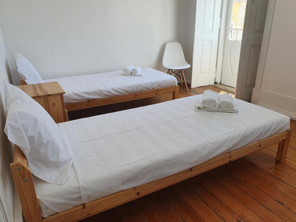 a bedroom with two beds with white sheets and shoes at Baixa Terrace Hostel in Faro
