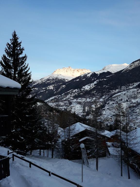 a snow covered mountain with a house in the foreground at Appartement dans chalet typiquement savoyard au pied des pistes in La Norma