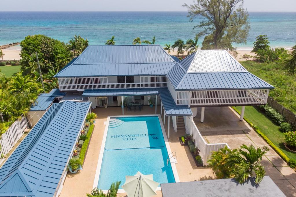 an aerial view of a house with a swimming pool and the ocean at Villa Turrasann in Runaway Bay