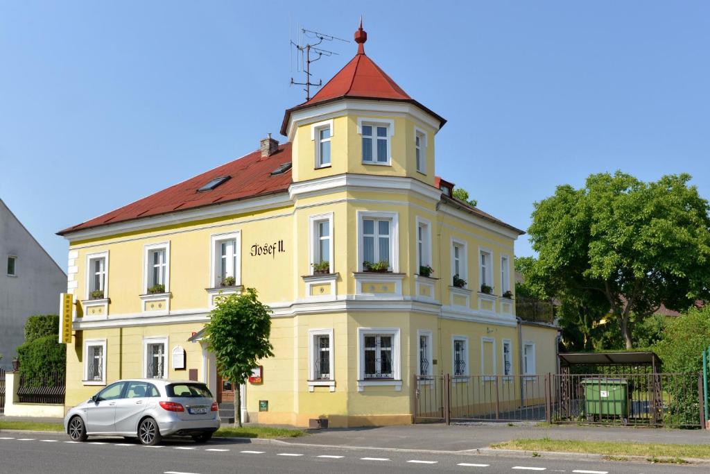 ein gelbes Gebäude mit rotem Dach mit einem Auto, das vorne parkt in der Unterkunft Pension Josef in Franzensbad