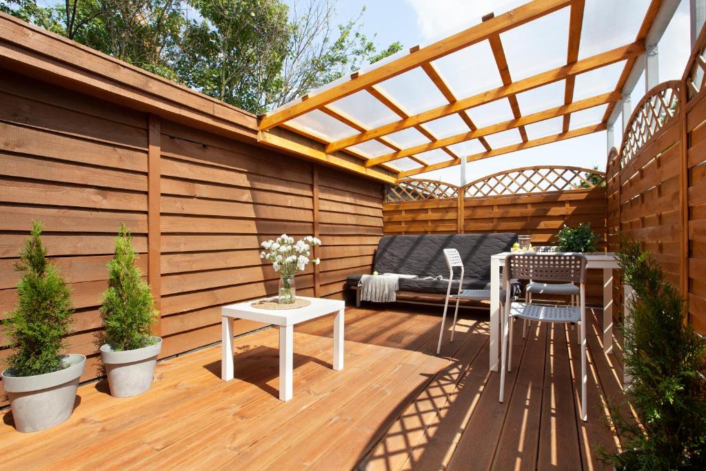 a wooden deck with a pergola and a table and chairs at RJ Hostel Chrobrego 79 in Gdańsk