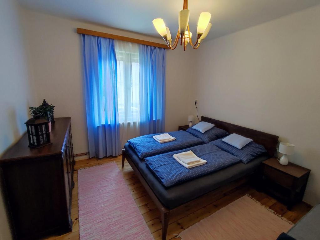 a bedroom with a bed with blue sheets and a window at Babka House in Banská Štiavnica
