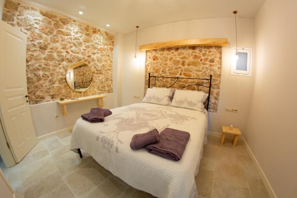 a bedroom with a bed and a stone wall at Villa Markezinis in Lákones