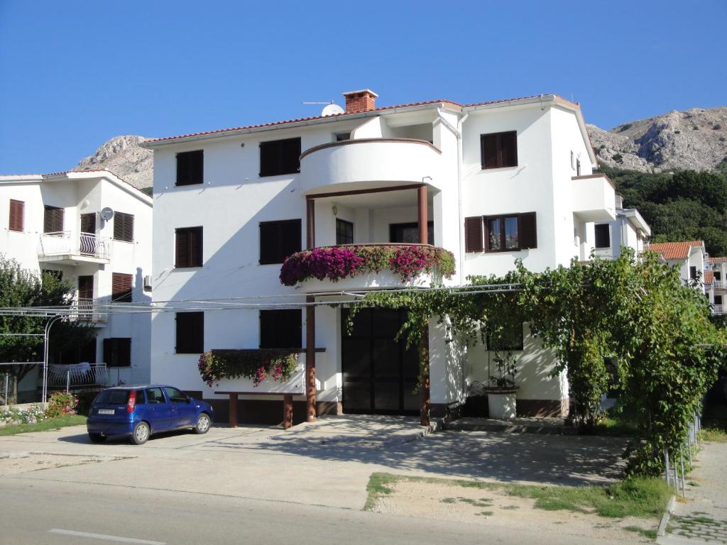 un edificio blanco con un coche aparcado delante de él en Apartments Grozdana, en Baška