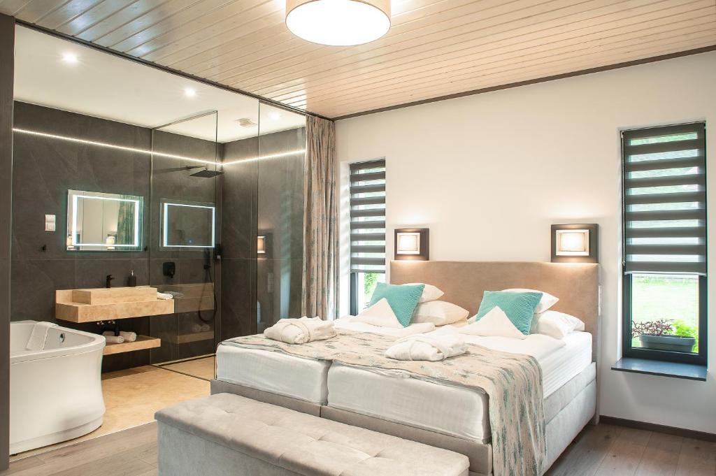 ein Schlafzimmer mit einem großen Bett, einer Badewanne und einem Waschbecken in der Unterkunft Dunazug Plusz Luxus Apartman in Dömös