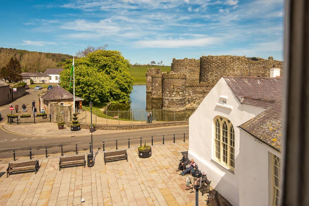 a building with benches and a castle and a lake at Castle Court in Beaumaris