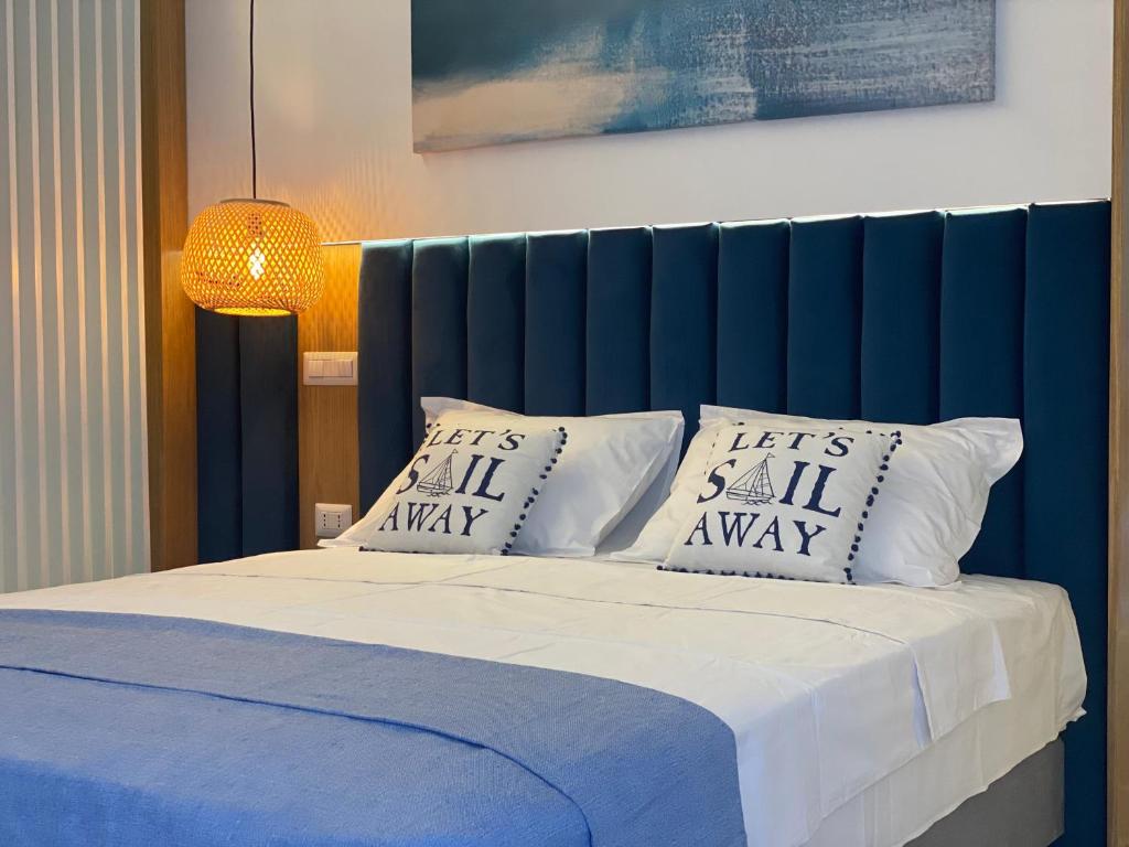 a bed with two pillows and a blue head board at GoConcept Studio Sardegna in Olbia