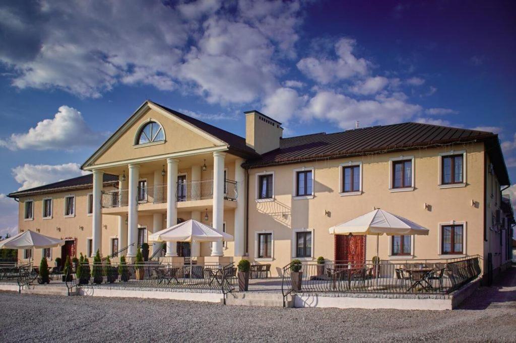 a large building with tables and umbrellas in front of it at Rezydencja Sandomierska in Sandomierz