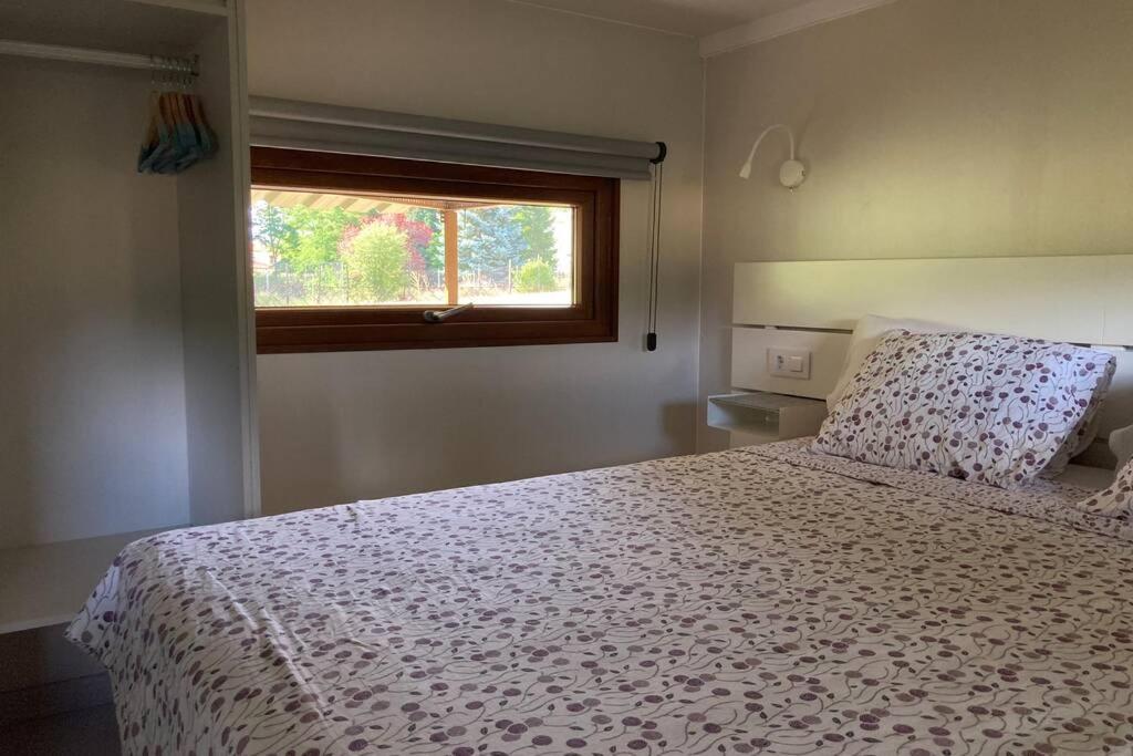 um quarto com uma cama com um edredão branco e uma janela em Cabaña El Verdinal em Uña