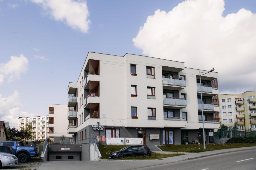 a white building with cars parked in front of it at Apartament 15 in Kościerzyna