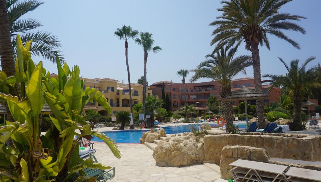 a resort with a pool and palm trees and buildings at Limnaria Gardens Paphos, near beach in Paphos