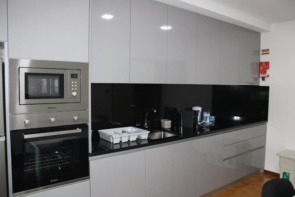 uma cozinha com armários brancos e um micro-ondas em APARTAMENTO CIDADE NOVA em Viana do Castelo