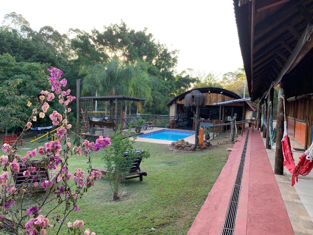 a garden with a swimming pool and a building at Chalé Dom Quixote in São Pedro