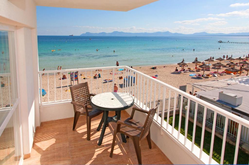 a balcony with a table and chairs and a beach at Mar Blau in Port d'Alcudia