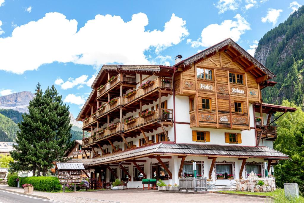 un grand bâtiment en bois dans les montagnes dans l'établissement Hotel Salvan, à Campitello di Fassa