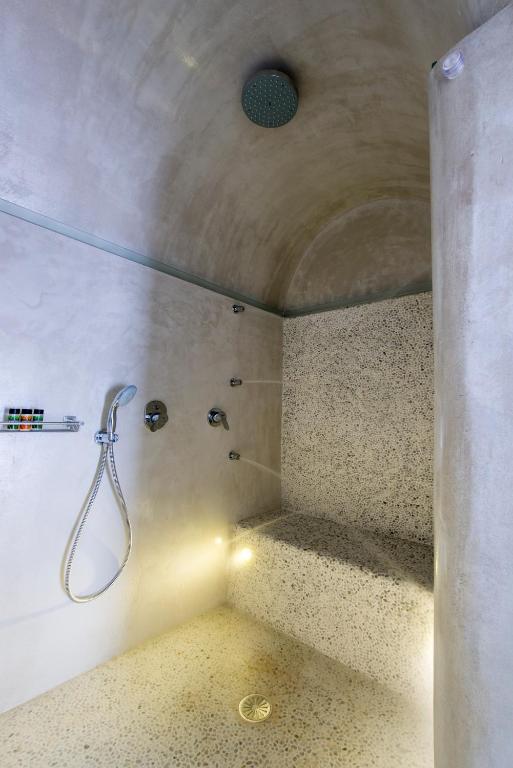 a bathroom with a shower with a hose on the wall at Villa Renos Hotel in Fira
