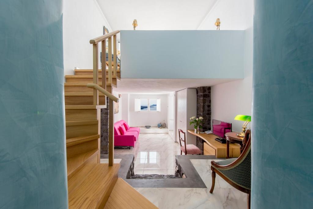 a living room with a staircase and pink furniture at Villa Renos Hotel in Fira