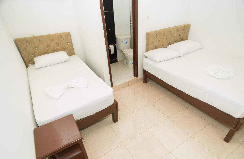 two beds in a small room with a mirror at Hotel Clau in Nuquí