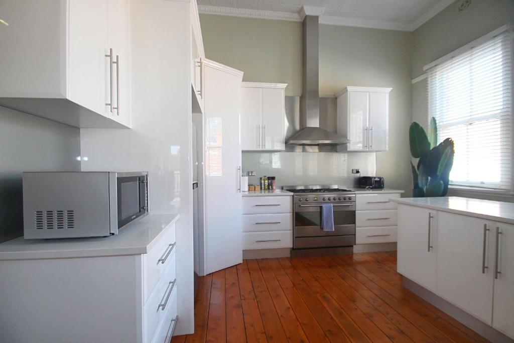 a kitchen with white cabinets and a wooden floor at Waterviews - Hidden Gem in CBD - Sleeps 10 in Wagga Wagga