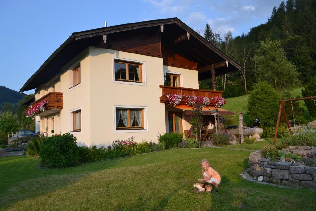 a woman sitting in the grass in front of a house at Ferienwohnung Haus Aschauer in Oberau