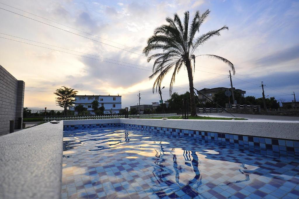 a swimming pool with a palm tree and a palm tree at M2 Villa in Dongshan