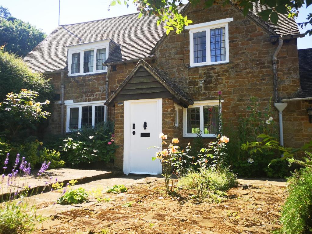 una casa de ladrillo con una puerta blanca en Spring Cottage en Banbury