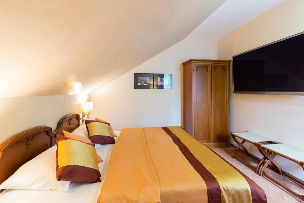 ein Hotelzimmer mit einem großen Bett und einem Flachbild-TV in der Unterkunft Hotel Sacher Baden in Baden